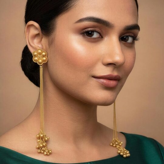 Model wearing long gold Kashmiri chain earrings with floral stud and ghungroo drops styled with green outfit.