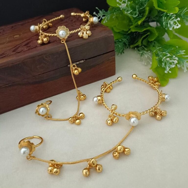 Delicate gold bracelet set with pearl detailing, floral charm design and adjustable fit.