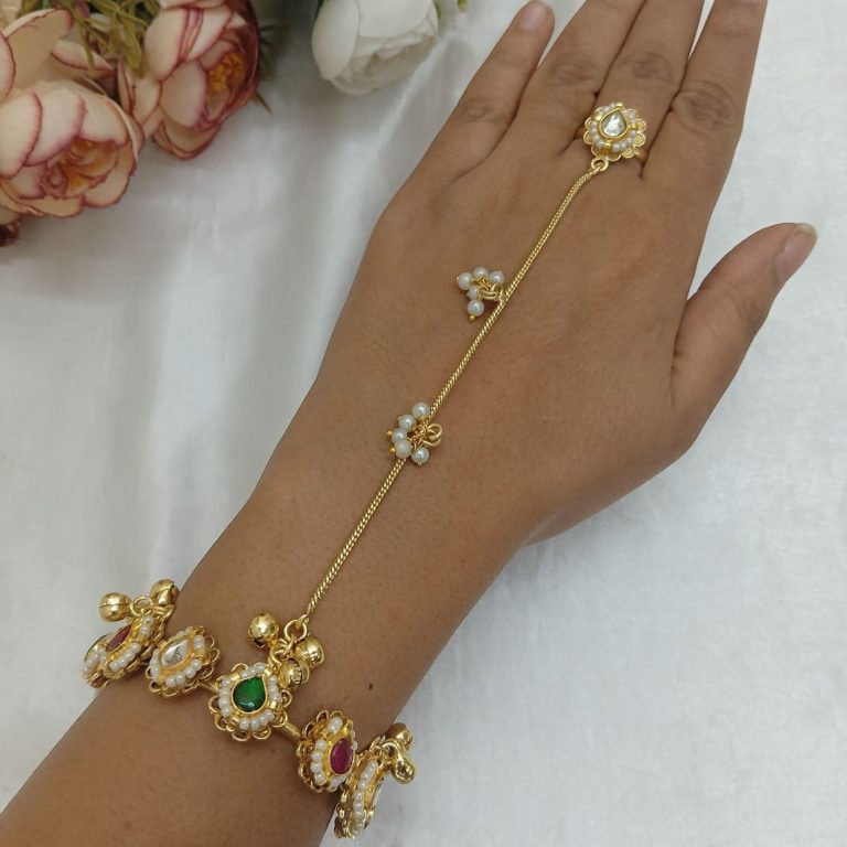Gold pearl haathphool bracelet with colorful stone detailing, finger ring chain design, and ghungroo charms.